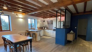 Una cocina amplia con vigas de madera, un comedor con mesa y sillas de madera, y una pared de acento azul.