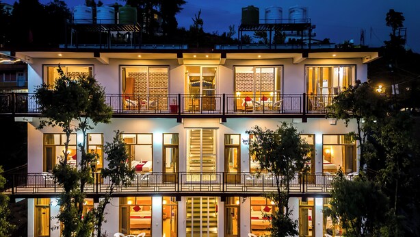 Un hôtel à plusieurs étages doté de balcons, de grandes fenêtres et d’une piscine.
