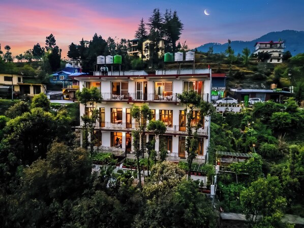Un hotel de varios pisos con balcones, un estacionamiento y vistas del paisaje circundante.