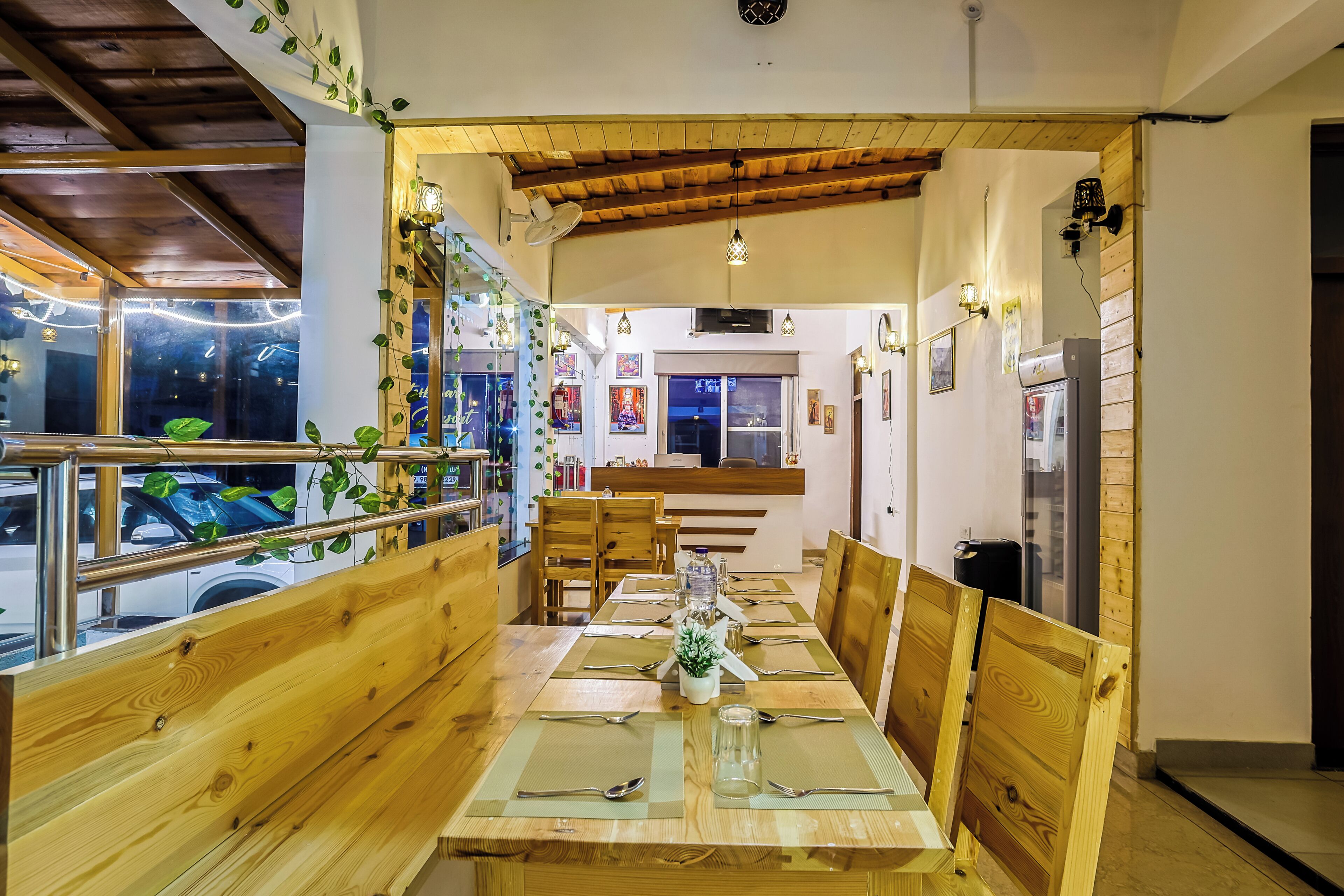 A dining area with wooden furniture, a glass table, and a view of the street outside.