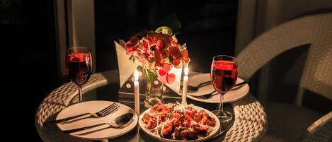 A dining table set with plates, cutlery, and glasses, accompanied by a candle holder with candles and a vase of flowers.