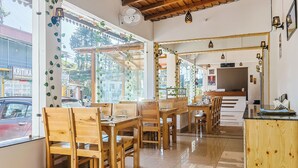 Un restaurant avec des meubles en bois, de grandes fenêtres et un sol carrelé.
