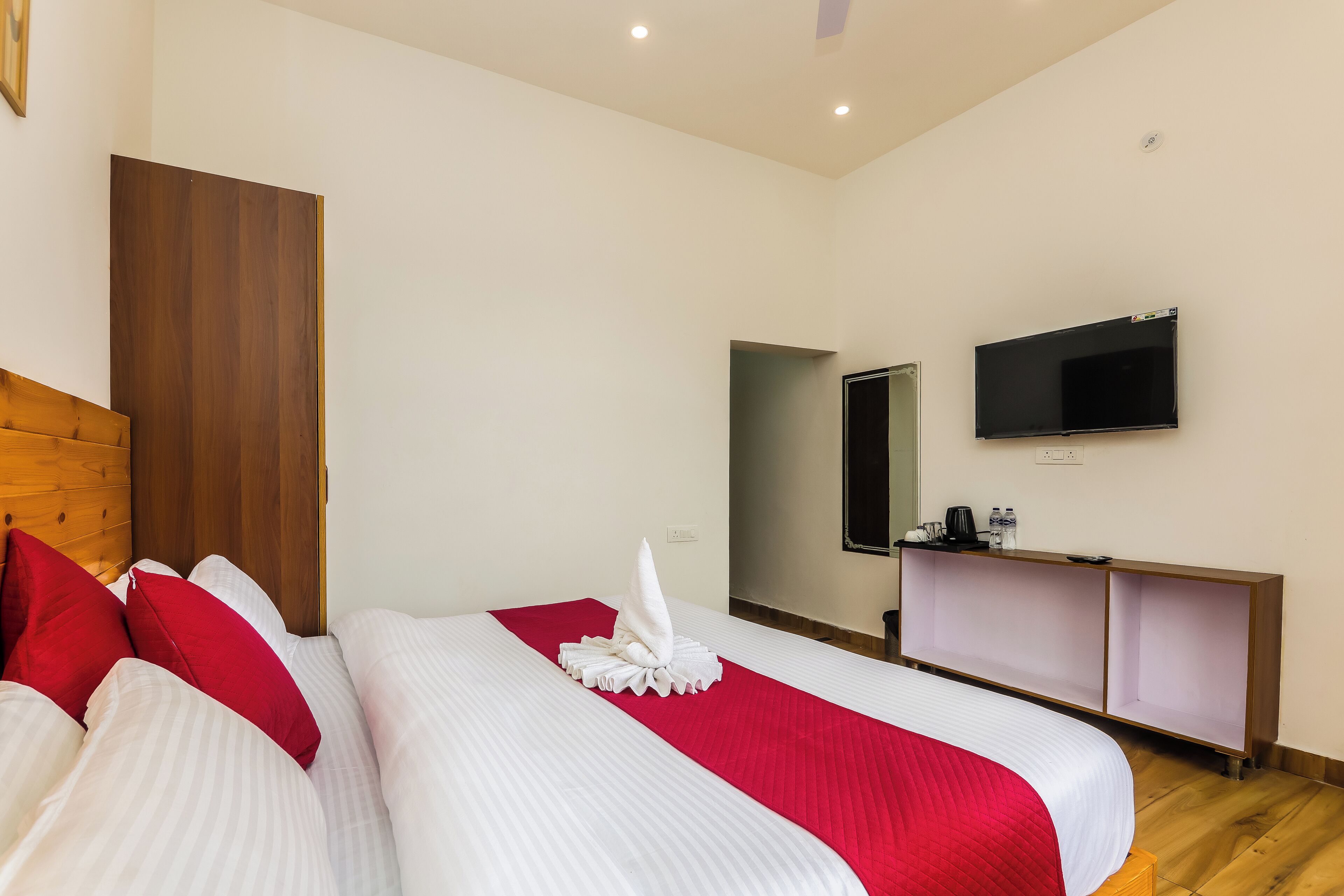 A hotel room with two beds, a wooden headboard, a TV, and a small desk with a mirror.