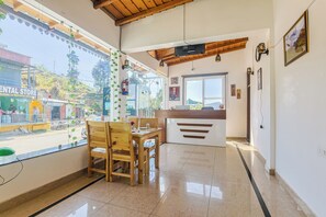 Habitación de hotel con techo de madera, un mostrador de recepción, una ventana con vista a la calle y suelo de baldosas.