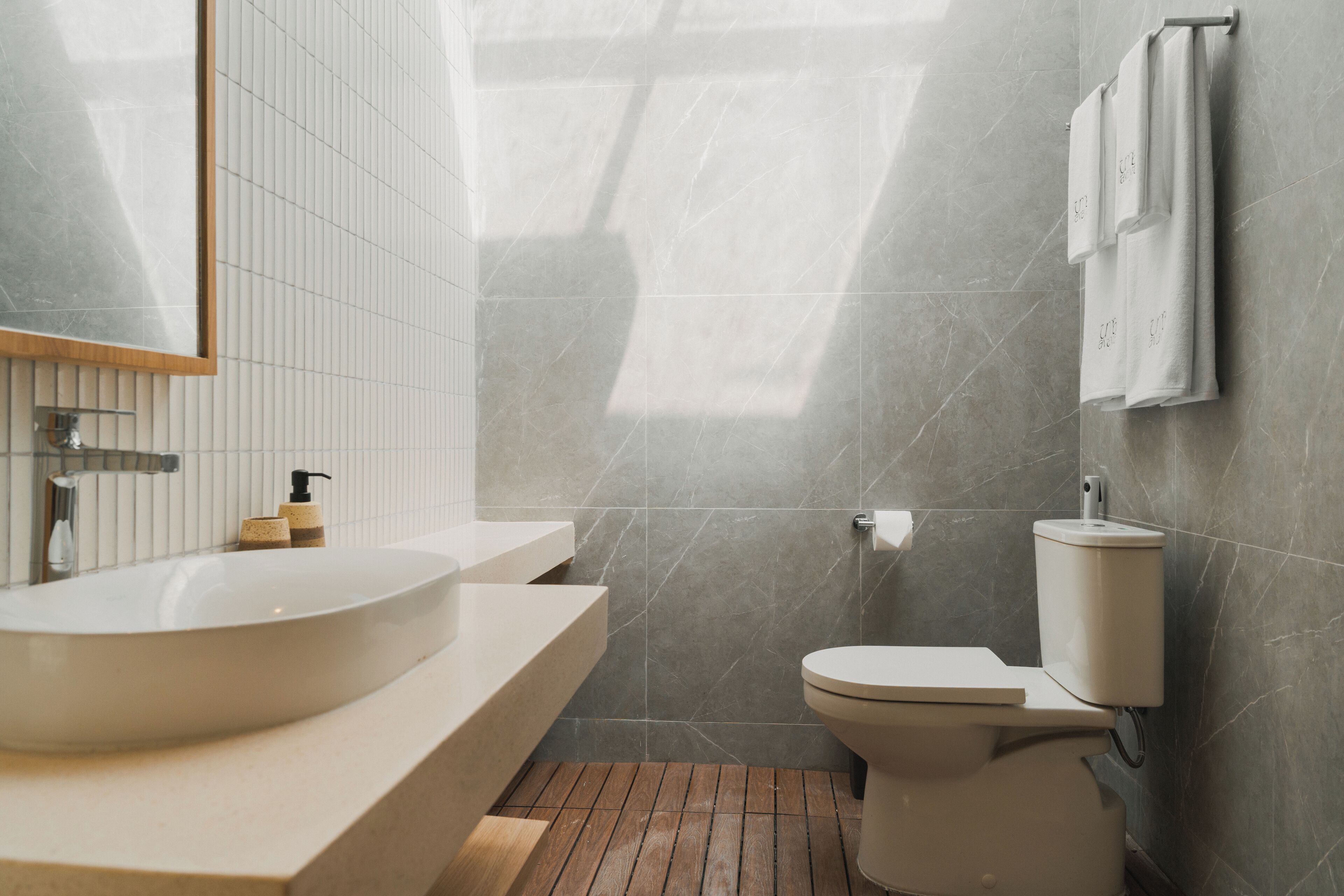 Un baño moderno con un lavabo grande, inodoro y espejo.