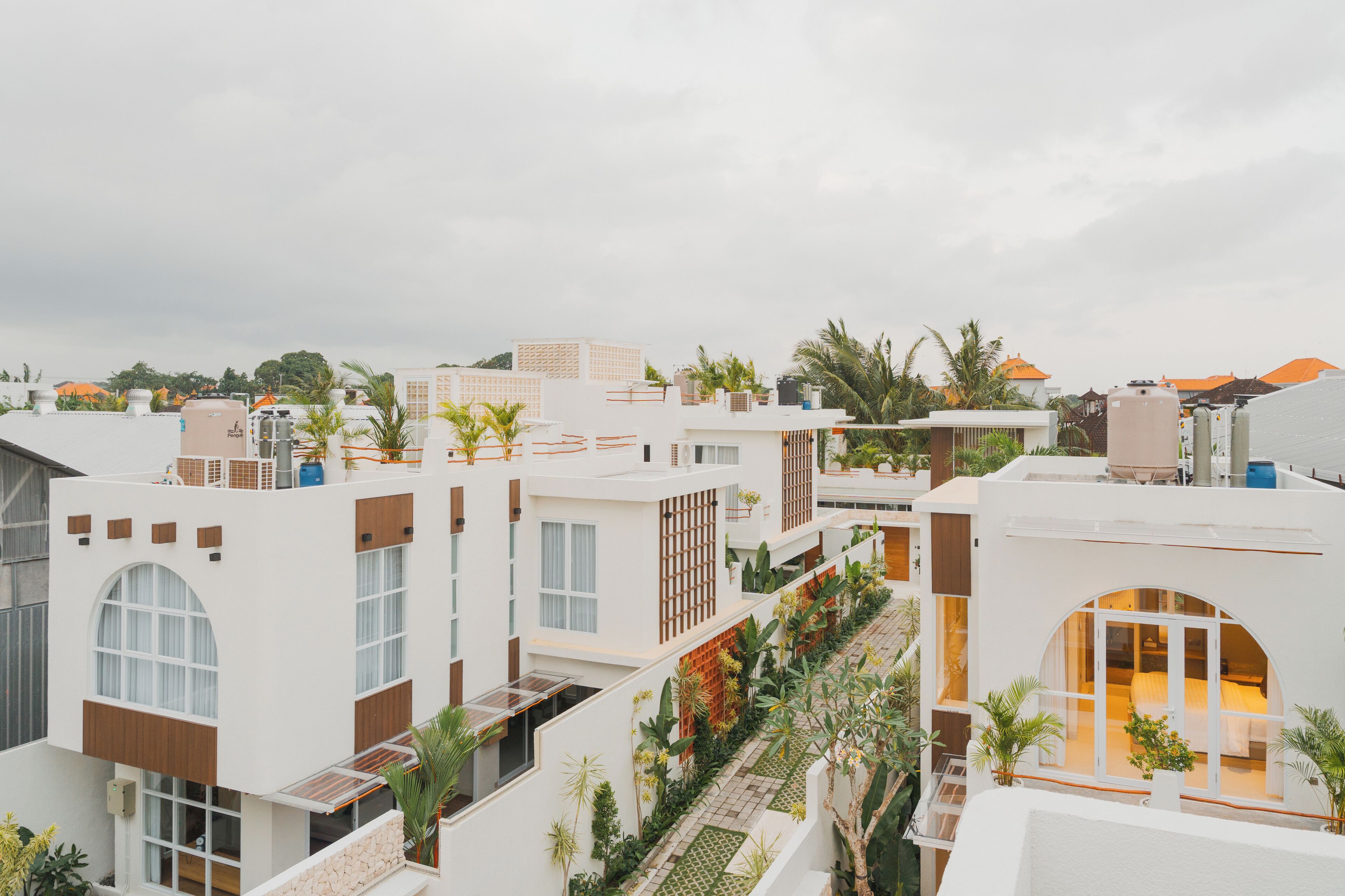 A modern hotel with multiple floors, large windows, and a central courtyard with plants.