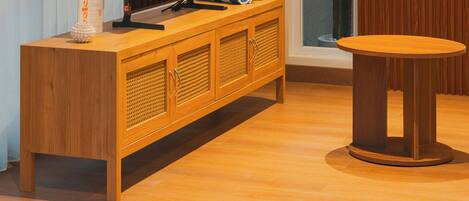 Una sala de estar moderna con un mueble bajo para televisor de madera, una mesa redonda y un ventanal con cortinas.