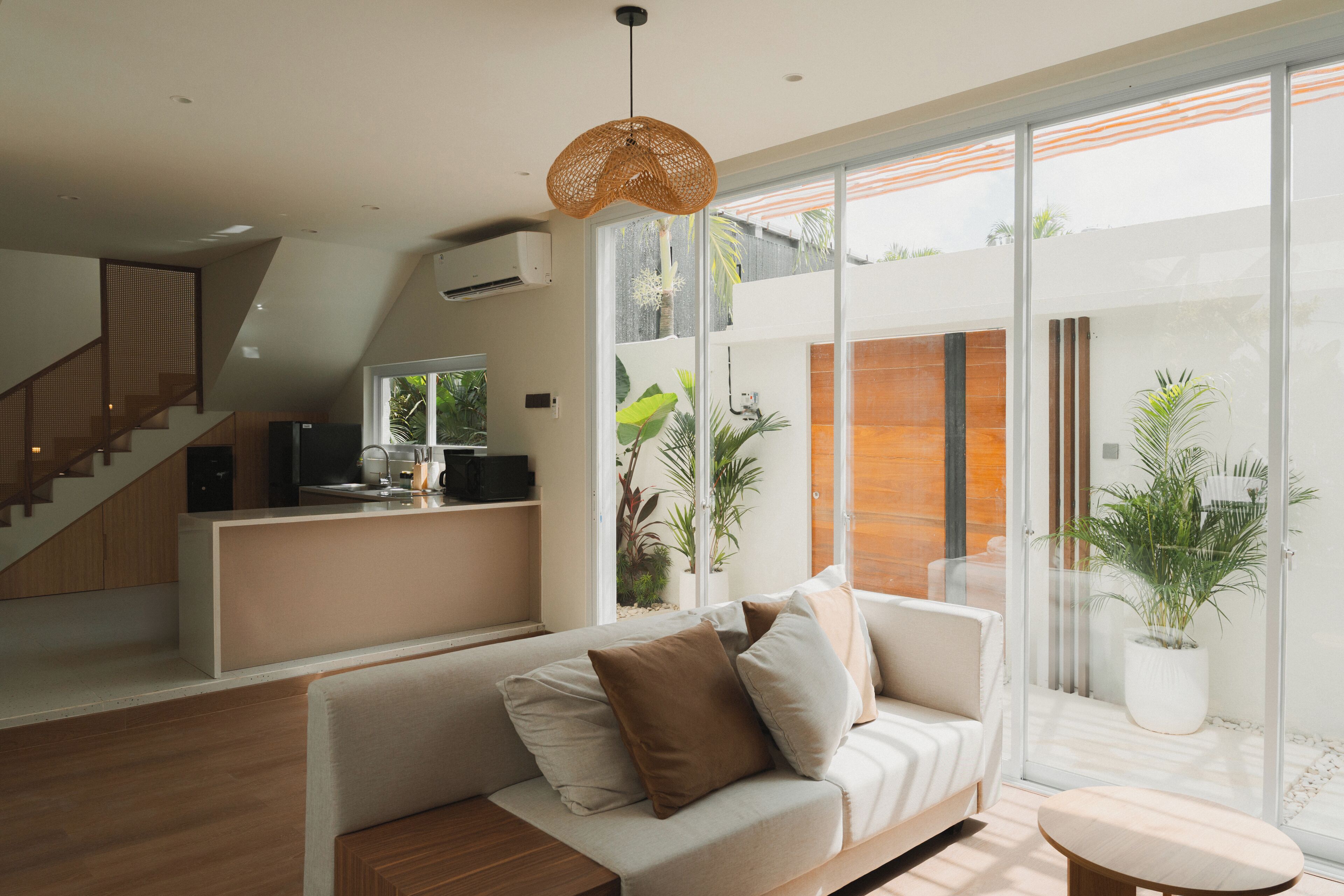 Un salon moderne avec un canapé, une table basse et une grande fenêtre donnant sur l’extérieur.