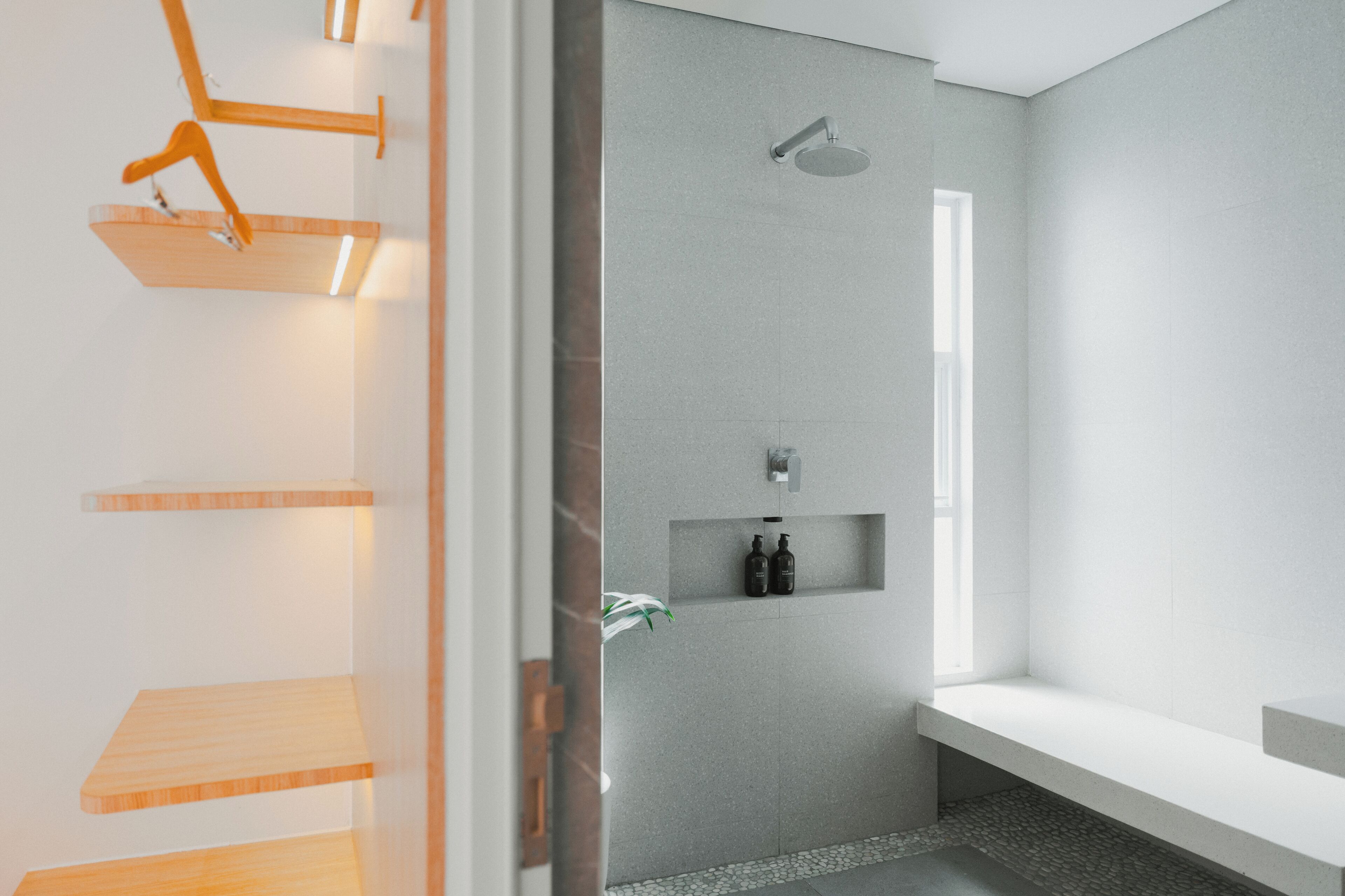 Une salle de bain moderne avec une douche, des étagères intégrées et un banc.
