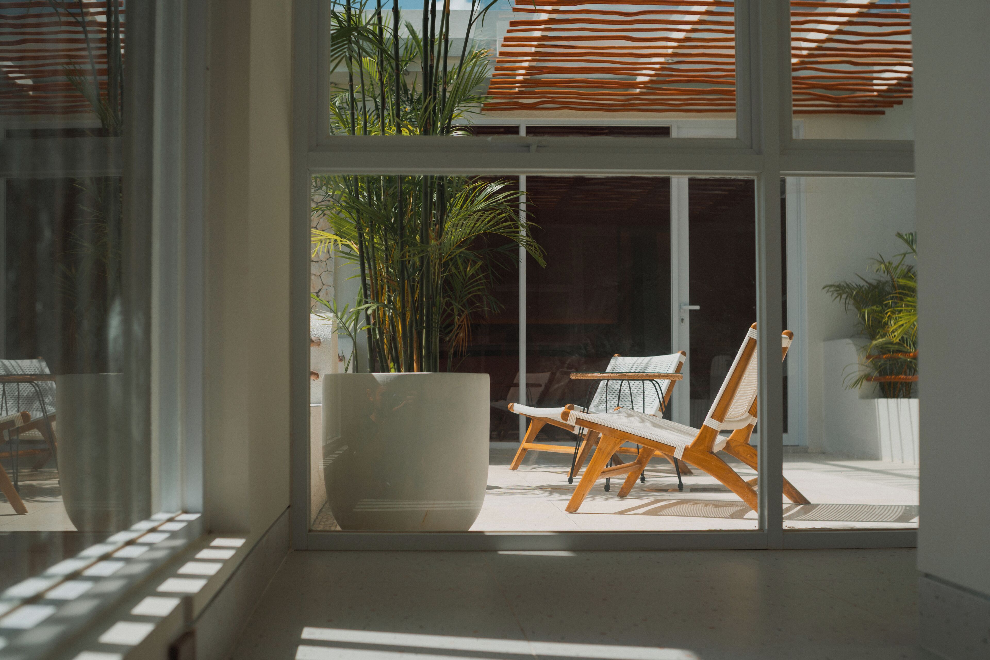 Een modern interieur met grote glazen deuren die leiden naar een buiten zitgedeelte, met een witte stoel en een tafel.