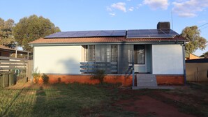A single-story house with a tiled roof, solar panels, and a small front porch. - The Sundown Stay (Dubbo)