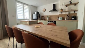 A modern kitchen with a wooden island, built-in appliances, and a clock on the wall.