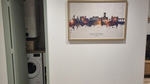 A room with a framed cityscape artwork on the wall, a washing machine, and a water heater in the corner.