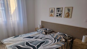 A bedroom with a bed, a nightstand, and three wall art pieces.