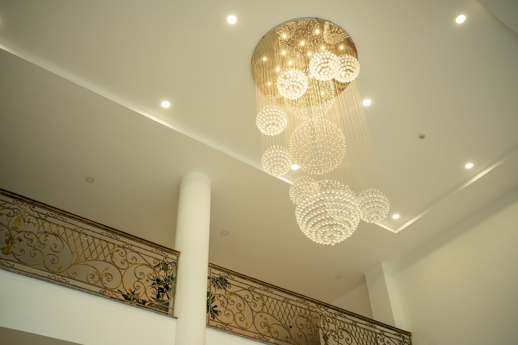 Een plafond met een decoratieve kroonluchter en een sierlijke balustrade met ingewikkelde details.