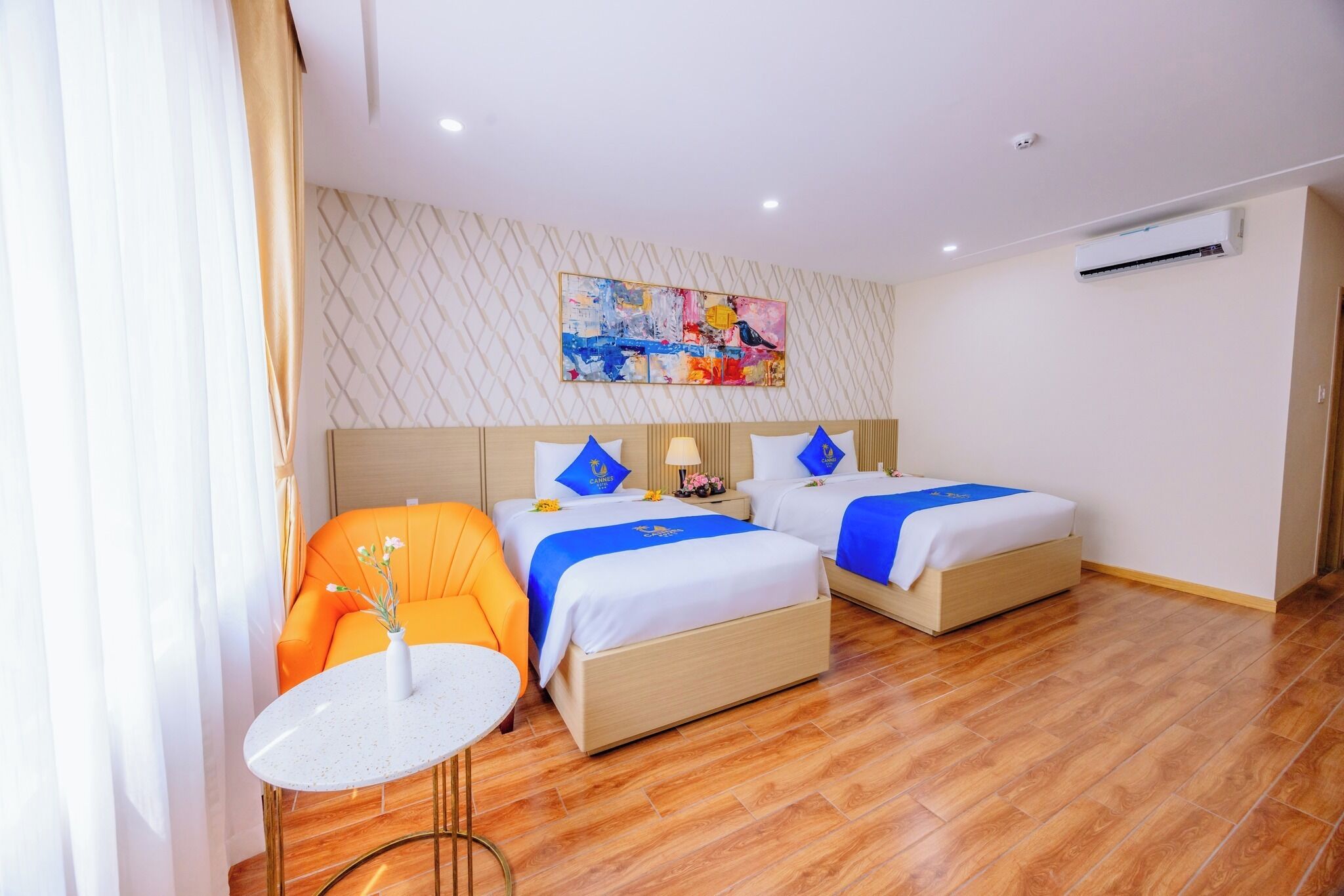 Habitación de hotel con dos camas, una mesita redonda y un sofá.