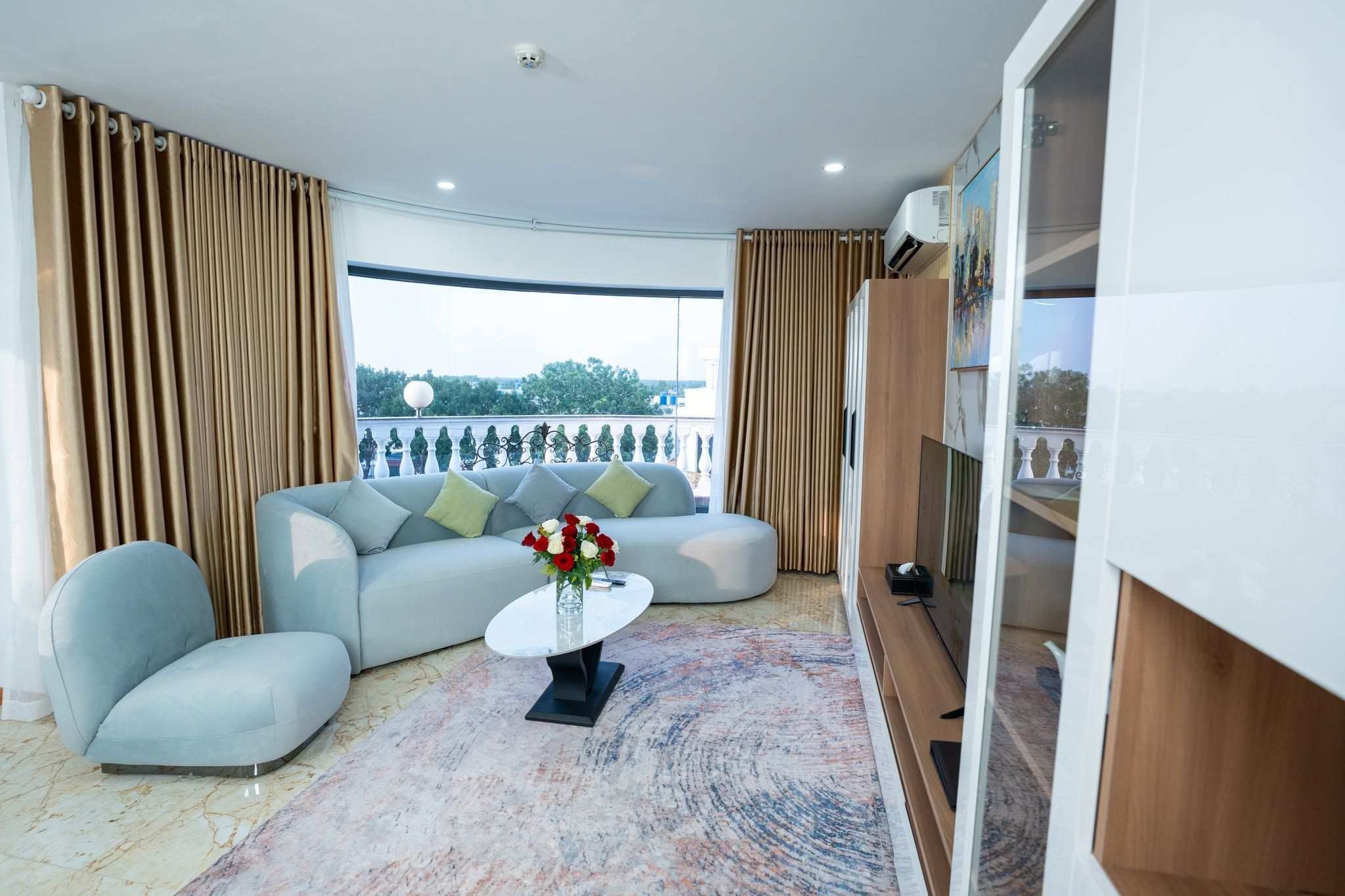 A modern living room with a sofa, armchairs, a coffee table, and a view of the outdoors.