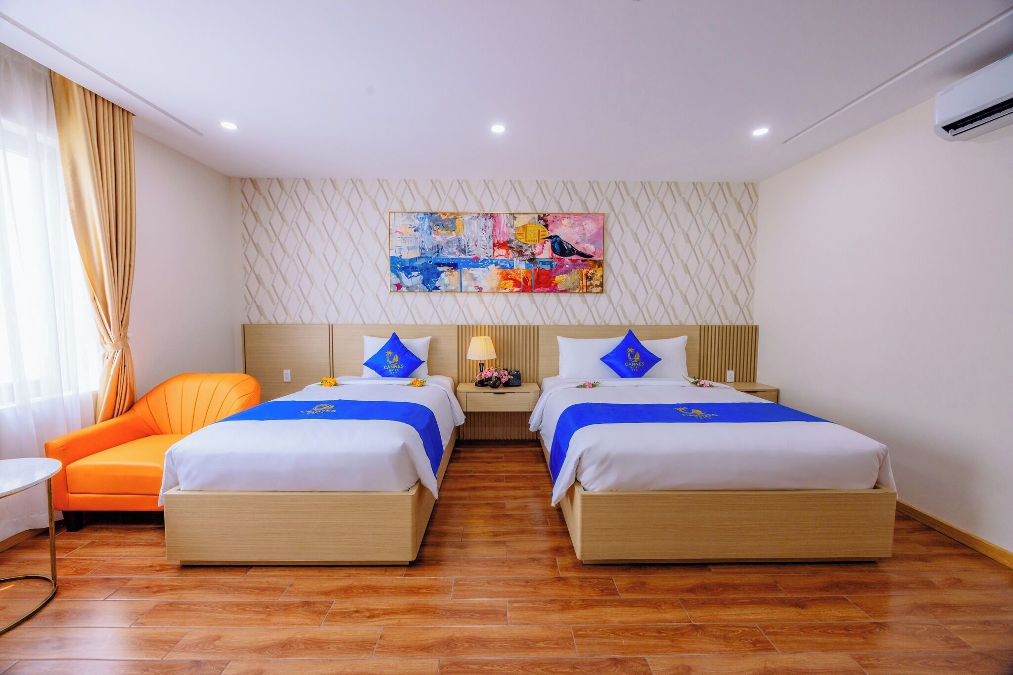 A hotel room with two beds, a nightstand, a chair, and a painting on the wall.