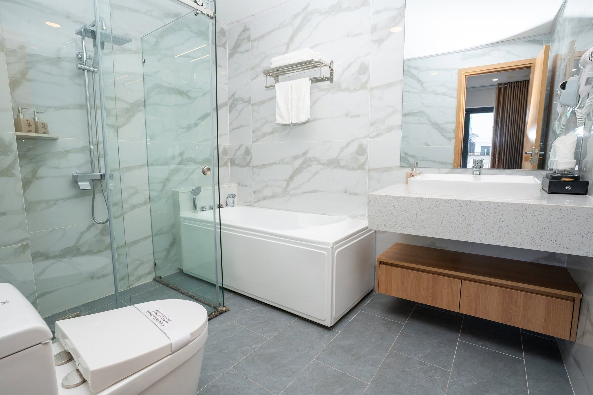 Une salle de bain moderne avec une douche à parois de verre, une baignoire blanche et un meuble-lavabo avec un miroir.