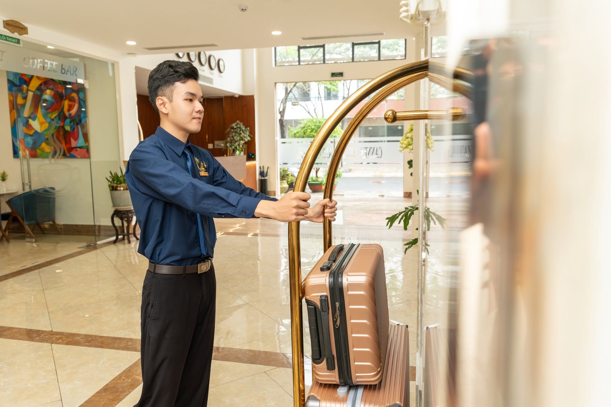 A hotel reception area with a luggage stand, a coffee bar, and a colorful abstract painting.