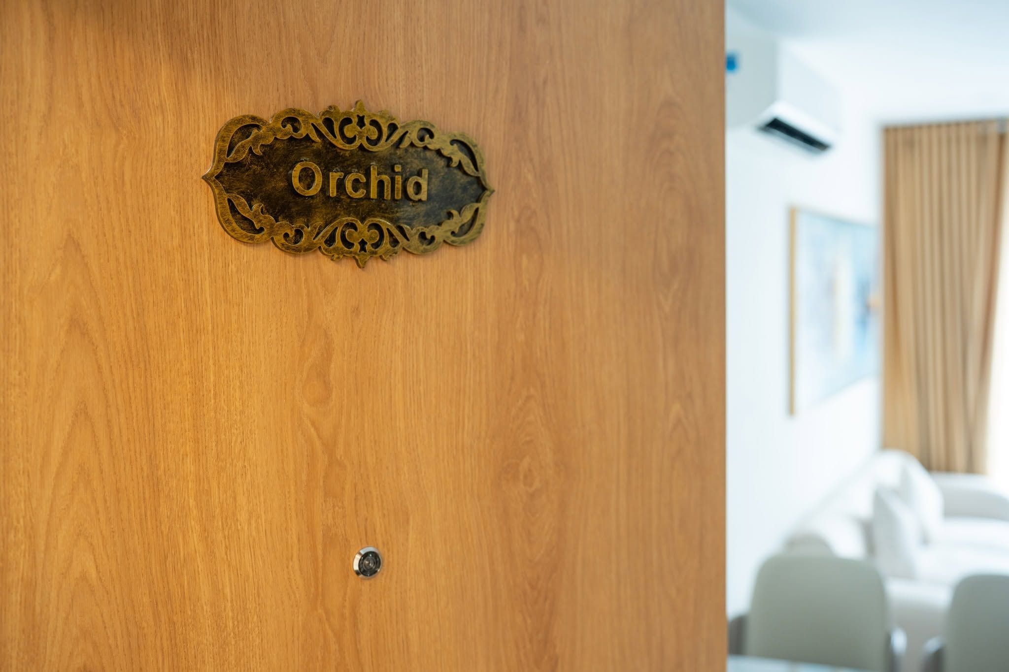 Een houten deur met een messing plaquette waarop 'Orchidia' staat.