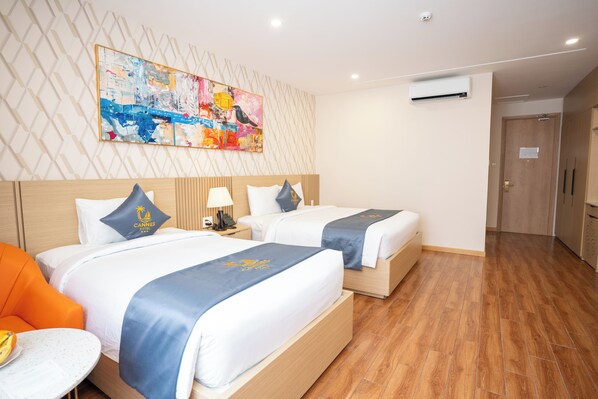 A hotel room with two beds, a painting on the wall, and a wooden floor. - Cannes Hotel (Phu Khuong)
