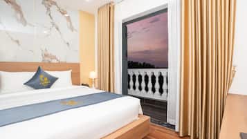 Una habitación de hotel con una cama, una mesita de noche, una lámpara, una ventana con cortinas y vistas al cielo.