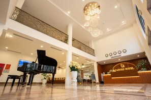 A hotel lobby with a grand piano, a reception desk, and a chandelier. - Cannes Hotel (Phu Khuong)