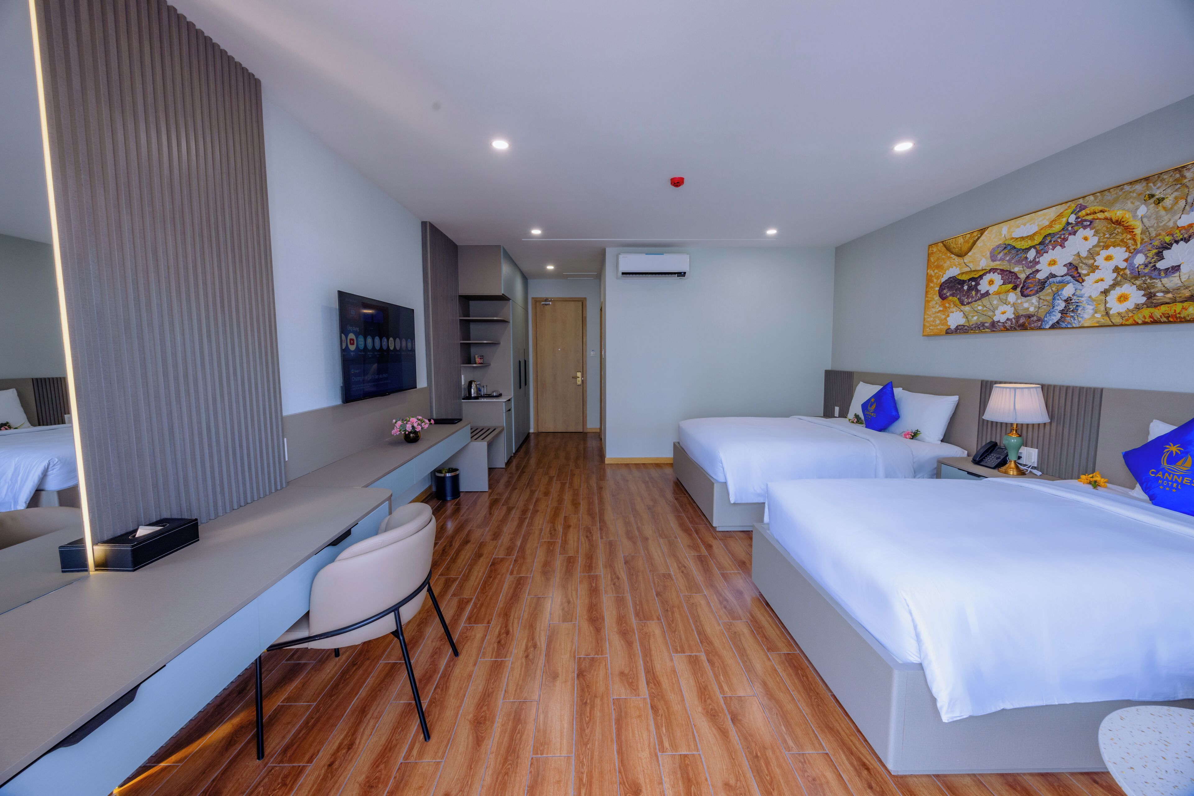 Une chambre d’hôtel avec deux lits, un bureau, une chaise, une télévision et un tableau au mur.