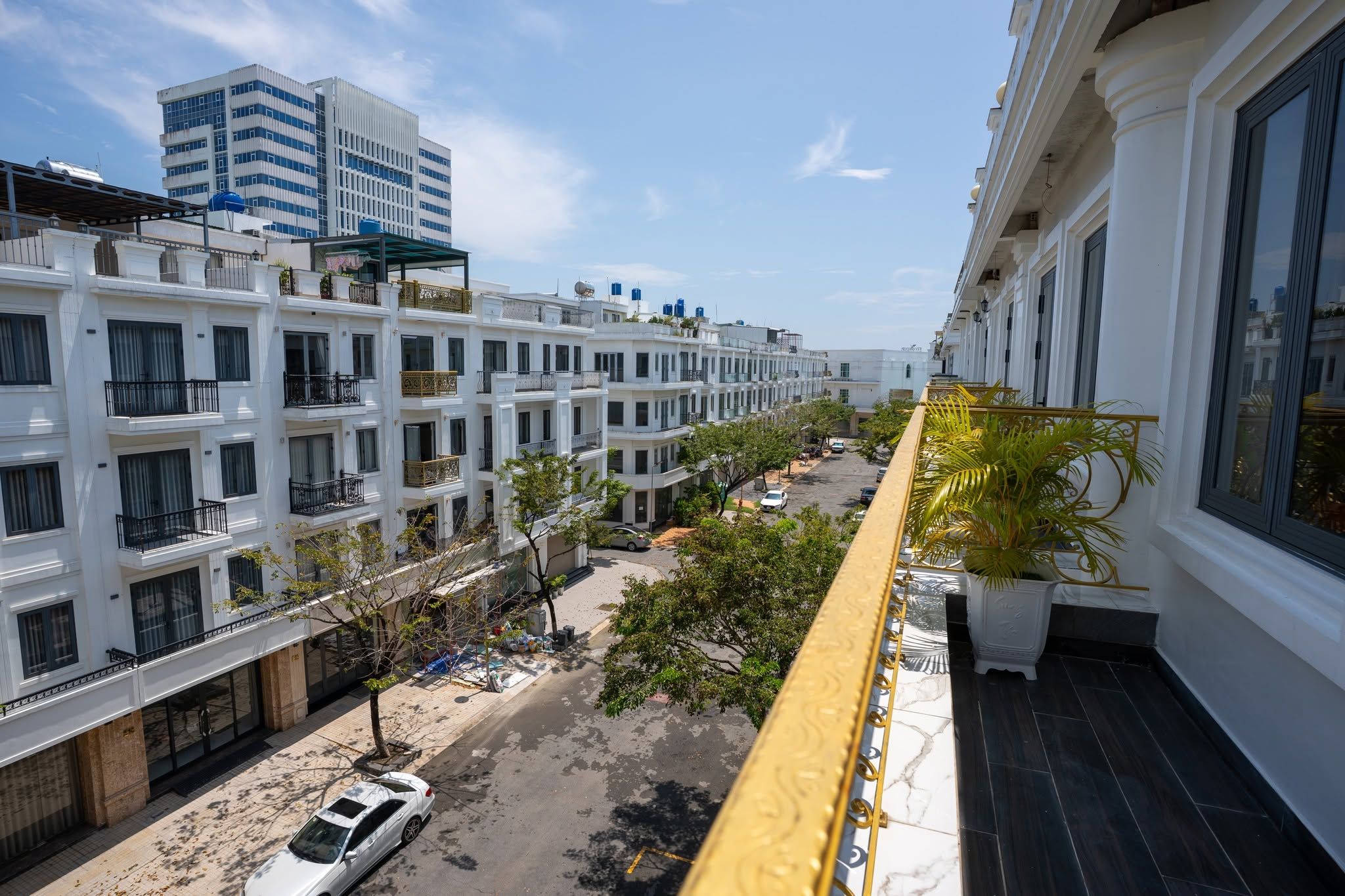 Un edificio residencial de varios pisos con balcones, vista a la calle y cielo despejado.