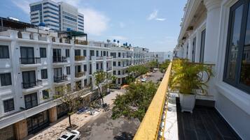 Un edificio residencial de varios pisos con balcones, vista a la calle y cielo despejado.