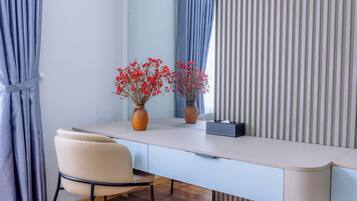Een modern bureau met een stoel, twee vazen met rode bloemen, een spiegel en een gestreept gordijn.