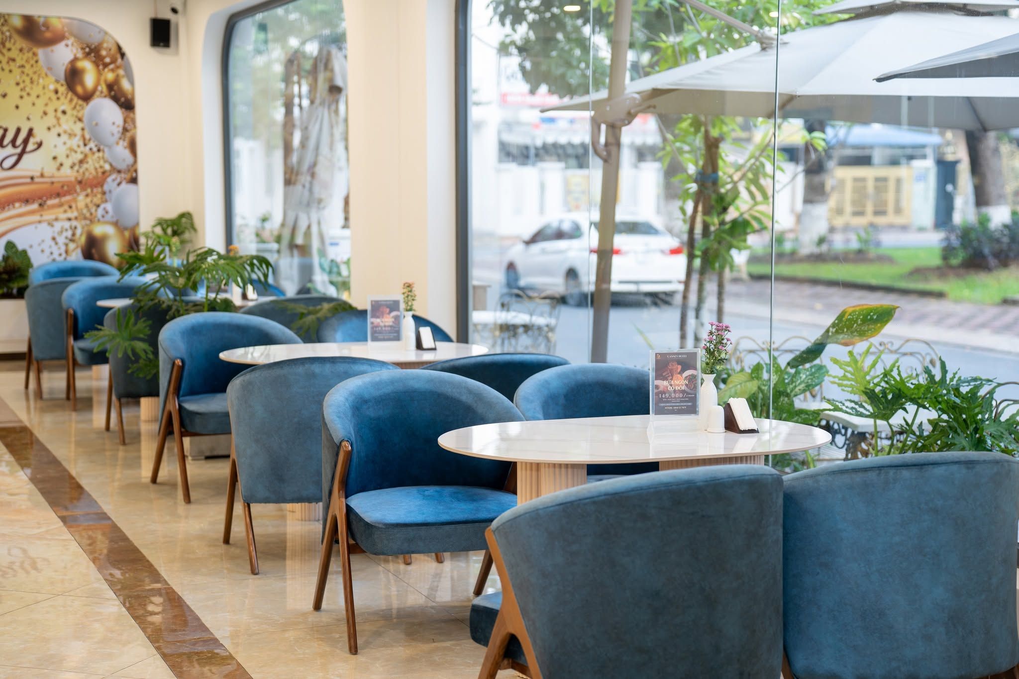 Eine Reihe blauer Stühle und Tische in einem Café mit Blick auf die Straße.
