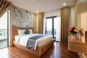 Une chambre d’hôtel avec un grand lit, une vue sur la ville et un balcon avec des rideaux.