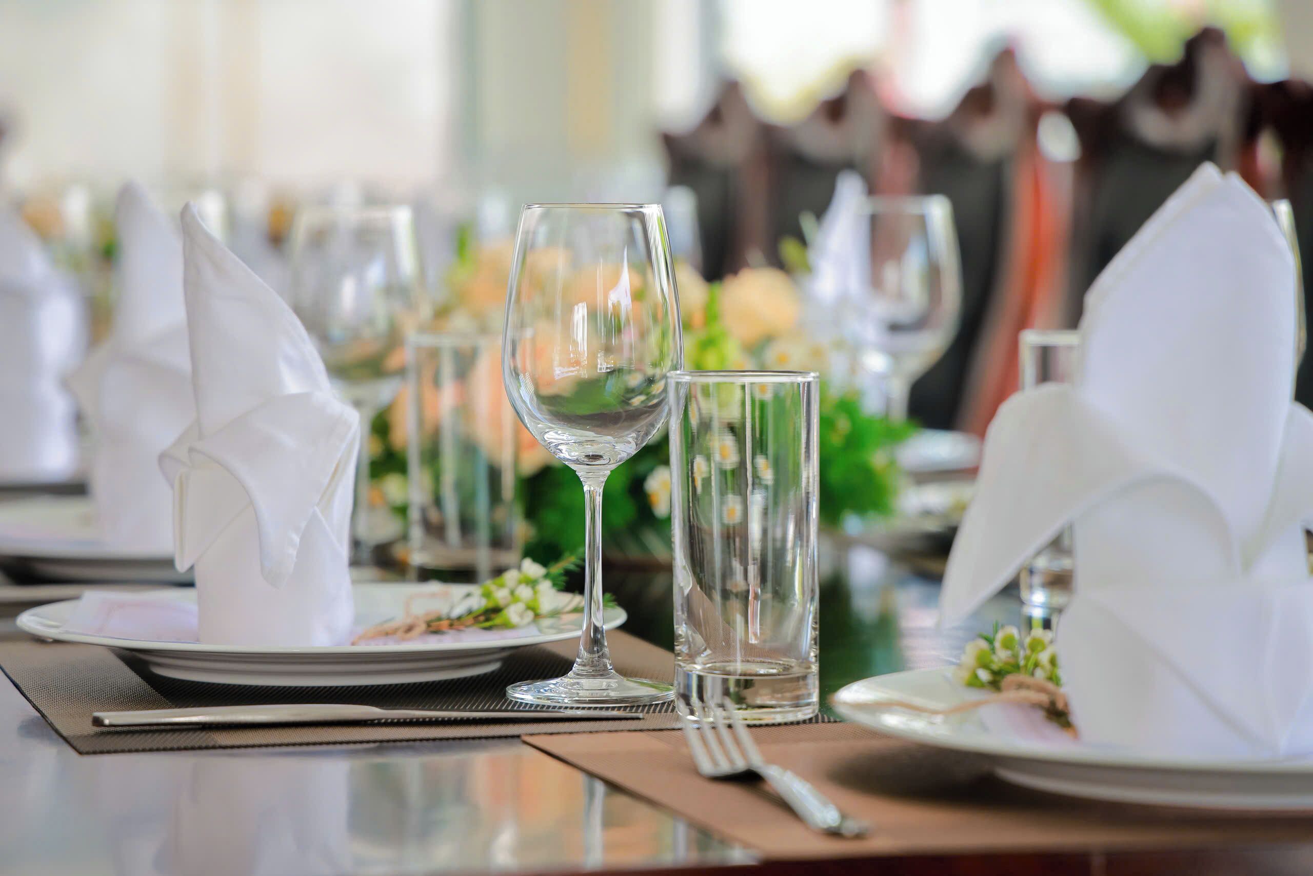 Una mesa de comedor preparada con servilletas blancas, copas de vino transparentes y un vaso de agua.