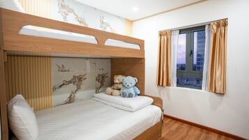 Un letto a castello con testiera in legno, una finestra con tende e un orsetto sul letto.