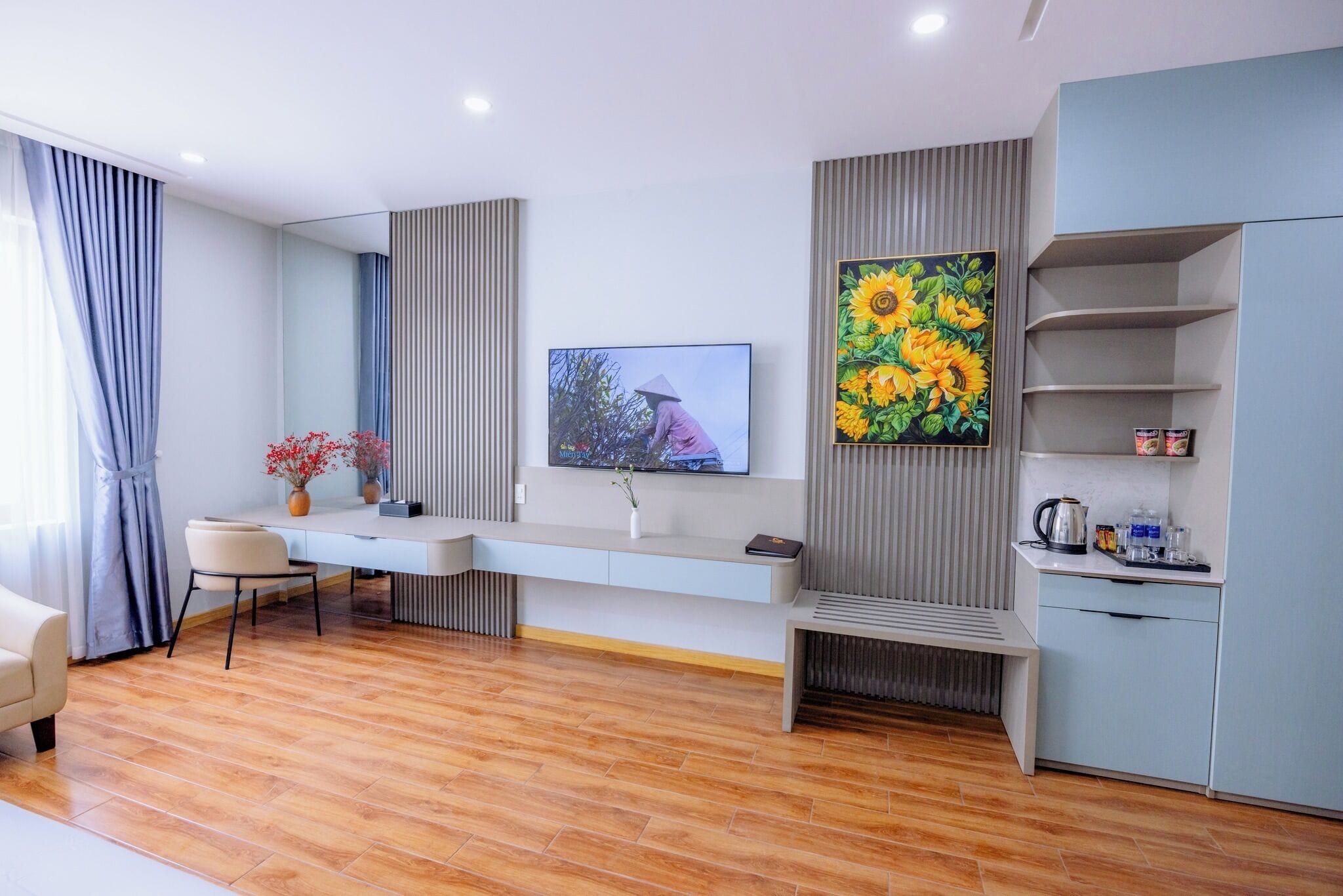 Una sala de estar moderna con una consola blanca alargada, un televisor montado en la pared y un cuadro grande de un girasol.