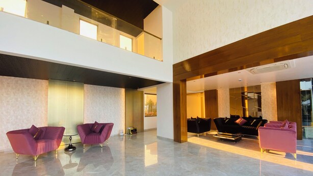 A spacious lobby with a high ceiling, marble flooring, and modern furniture including purple and black sofas. - The Manak Bagh (Sehore)