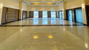 A spacious, well-lit hall with a polished floor, large chandeliers, and a view of the outdoors through large windows. - The Manak Bagh (Sehore)