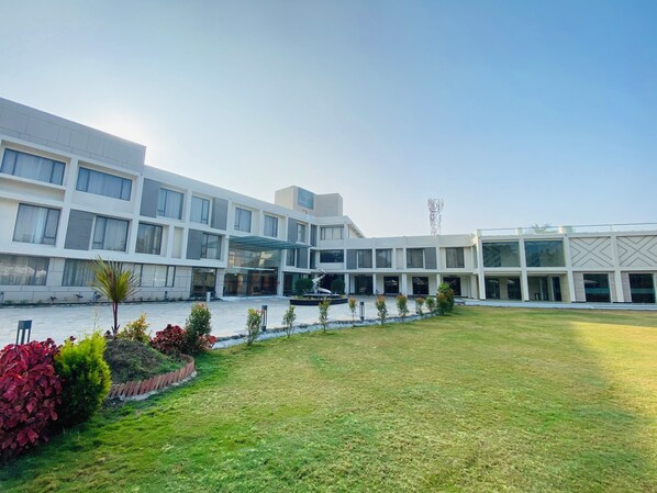A modern hotel with a central courtyard, multiple floors, and a prominent glass entrance. - The Manak Bagh (Sehore)