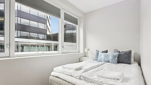A bedroom with a bed, a nightstand, and a window overlooking a building. - Top apartment with high standard in the city center. Terrace and walking distance to Bryggen. (Vestland)