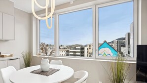A modern kitchen with white cabinetry, a round dining table with white chairs, and a large window offering a city view. - Top apartment with high standard in the city center. Terrace and walking distance to Bryggen. (Vestland)
