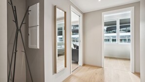 A modern room with a wooden floor, a coat rack, and a view of a balcony with a railing. - Top apartment with high standard in the city center. Terrace and walking distance to Bryggen. (Vestland)