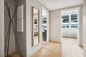 Une chambre moderne avec un plancher en bois, un porte-manteau et une vue sur un balcon doté d’une balustrade.