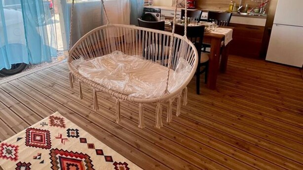 Ein Zimmer mit Hängesessel, Küchenzeile und einem gemusterten Teppich.