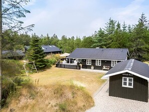 A lodge with a large deck area, surrounded by dense forest. - 4 Star Holiday Home in Blokhus (Blokhus)
