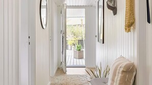A hallway with a wooden floor, a woven rug, a sofa, and a door leading to an outdoor area with plants. - 4 Star Holiday Home in Blokhus (Blokhus)