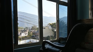 Habitación con un ventanal grande que da a una zona residencial y montañas.
