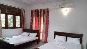 Una habitación de hotel con dos camas de madera, ropa de cama blanca, un pequeño tapete y una ventana con cortinas.