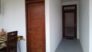 Un pasillo con una puerta de madera y una pequeña mesa con una silla.